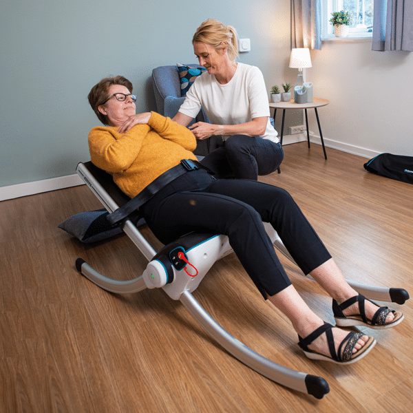 A single caregiver uses a modern Raizer II mobile lift chair to safely assist an elderly woman rising effortlessly from the floor in a living room.